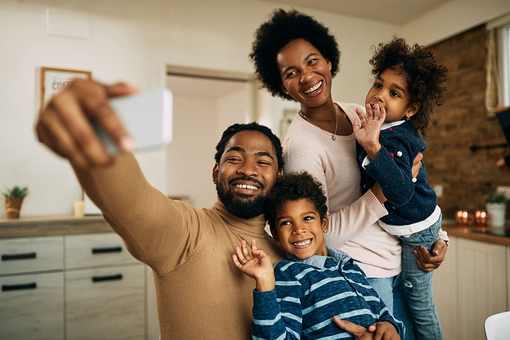 Happy black parents with kids making video call over smart phone